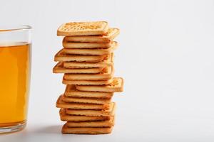 uma pilha de biscoitos de trigo dourado e uma caneca de chá verde perfumado em um fundo branco. biscoitos dispostos em uma coluna de café da manhã e um destaque dourado com canecas de chá foto