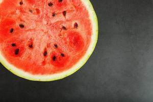 metade da melancia vermelha madura e saborosa sobre fundo preto, textura da polpa suculenta da melancia vermelha madura com sementes foto