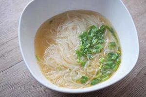 tigela de macarrão de aletria de arroz - tigela de sopa de macarrão de arroz com coentro em fundo de madeira foto