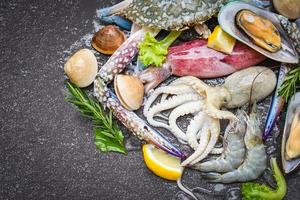 buffet de frutos do mar frescos com alecrim limão, ervas e temperos - frutos do mar no gelo congelados com camarões camarões caranguejo garras conchas mariscos lulas polvo e mexilhões no restaurante foto