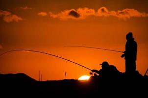 silhueta de pescadores ao pôr do sol foto