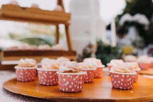 cupcakes gourmet com cobertura de creme de manteiga branco e confeitos em fundo de madeira foto