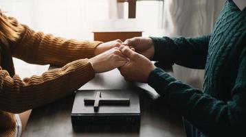 duas pessoas lendo e estudando a bíblia em casa e orando juntos. estudando a palavra de deus com os amigos. foto