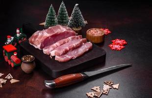pedaço fresco de carne de porco crua com especiarias, sal e ervas em uma tábua de madeira