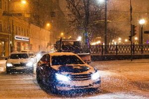 queda de neve na cidade noturna - tráfego de carros sob a neve foto