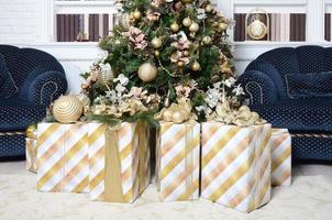 foto de caixas de presente de luxo sob a árvore de natal, decorações para casa de ano novo, embrulho dourado de presentes de papai noel, abeto festivo decorado com guirlanda, enfeites e brinquedos, celebração tradicional