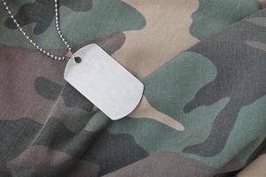 contas militares prateadas com placa de identificação no uniforme de fadiga de camuflagem foto