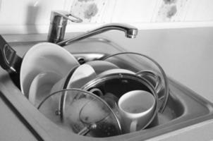 pratos sujos e utensílios de cozinha não lavados pia de cozinha cheia foto