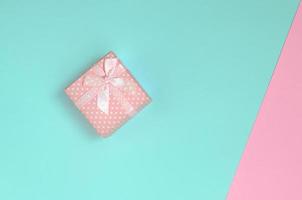 pequena caixa de presente rosa está no fundo de textura de papel de cores azul e rosa pastel de moda em conceito mínimo foto