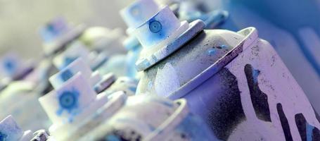muitas latas de aerossol sujas e usadas de tinta azul brilhante. fotografia macro com profundidade de campo rasa. foco seletivo no bico de pulverização foto
