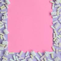 marshmallow colorido disposto em fundo de papel violeta e rosa. quadro texturizado criativo pastel. mínimo foto