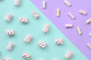 marshmallow colorido disposto em fundo de papel violeta e azul. padrão texturizado criativo pastel. mínimo foto