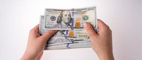 mão humana segurando notas de dólar americano em fundo branco foto