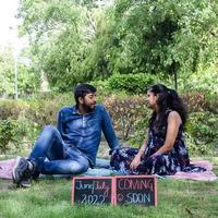 casal indiano posando para ensaio de maternidade. o casal está posando em um gramado com grama verde e a mulher está vacilando sua barriga no jardim lodhi em nova delhi, índia foto