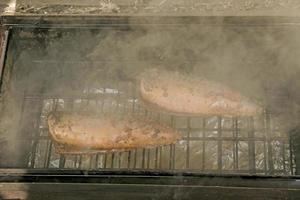 peixe cavala em uma marinada em uma grelha em um fumeiro. o processo de cozimento de cavala defumada quente foto