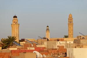 vista da paisagem urbana da cidade de tozeur na tunísia durante o pôr do sol com minaretes da mesquita ao fundo. medina de tozeur, cidade velha. local de interesse histórico. viagens e turismo na área do deserto. foto