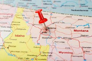 agulha clerical vermelha em um mapa dos eua, montana e a capital de helena. feche o mapa de montana com red tack foto