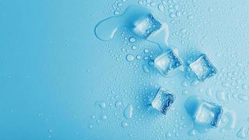 cubos de gelo com gotas de água derretida sobre um fundo azul, vista superior. foto