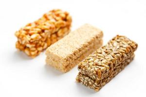 barra de granola de grãos com amendoim, gergelim e sementes seguidas em um fundo branco. vista superior três barras variadas, isolar foto