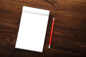 bloco de notas com lápis vermelho em um fundo de mesa de madeira marrom, para educação, escreva objetivos e ações foto