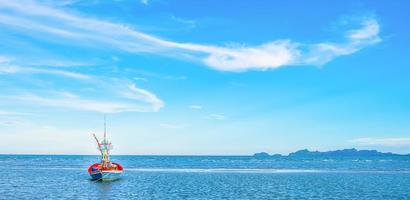 uma vista de um barco de pesca atracado à beira-mar pela manhã com um lindo mar azul e céu. foto