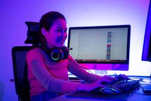 uma jovem jogadora ativa e séria em seu poderoso computador pessoal, jogando videogames online em primeira pessoa. foto