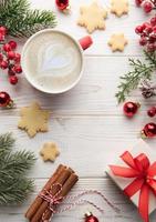 xícara de café com leite e decoração de natal em um fundo branco de madeira foto