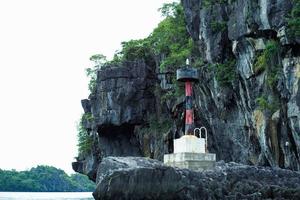 a torre do farol localizada na rocha no mar com o alto penhasco ao fundo foto
