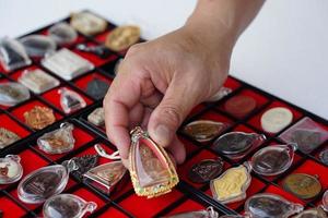 closeup mão segura amuleto de buda tailandês da coleção de amuletos. conceito, fé e crença para budista para santo e sorte. coleta de amuleto como passatempo, troca, venda ou compra foto