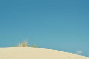 fundo de praia de verão, areia e céu azul de verão, ideia de férias à beira-mar, pano de fundo ou protetor de tela para publicidade foto