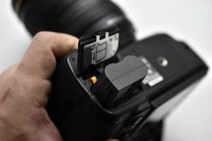 a bateria da câmera slr. trocando a bateria da câmera em close-up. a bateria da câmera está na mão do fotógrafo. foto