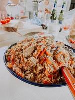 arroz pilaf com cenoura, especiarias em um prato bonito e pintado. cozinhar pilaf em um caldeirão. apetitoso prato de carne e arroz. Cozinha tradicional foto