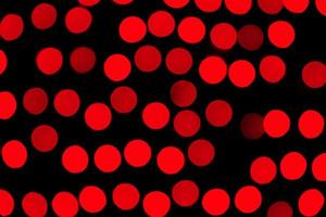 bokeh vermelho abstrato sem foco em fundo preto. desfocado e desfocado muitas luzes redondas foto