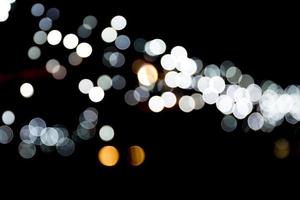 bokeh abstrato de luzes da cidade branca sobre fundo preto. desfocado e desfocado muitas luzes redondas foto