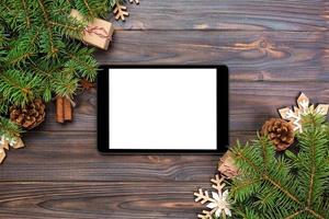 tablet digital simulado com decorações rústicas de fundo de madeira de natal para apresentação de aplicativos. vista superior com espaço de cópia foto