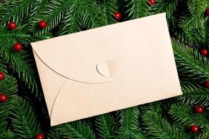 vista superior do envelope decorado com uma moldura feita de abeto em fundo de madeira. conceito de tempo de ano novo foto