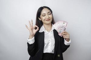 empresária asiática animada vestindo um terno preto dando um gesto de mão ok isolado por um fundo branco foto