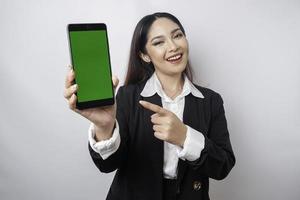 uma jovem empresária feliz está vestindo terno preto, mostrando espaço de cópia em seu telefone isolado por fundo branco foto