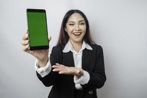 uma jovem empresária feliz está vestindo terno preto, mostrando espaço de cópia em seu telefone isolado por fundo branco foto