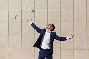 jovem empresário jogando dólares e dançando na rua foto