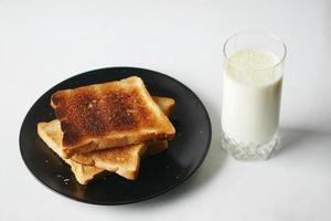 copo de leite e pão torrado na mesa foto