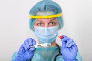 assistência médica segurando covid-19, kit de coleta de swab de coronavírus, usando luvas de máscara de traje de proteção, tubo de ensaio para coleta de amostra de paciente op np, processo de protocolo de teste de dna pcr foto