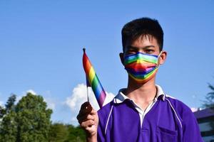 retrato de menino asiático segura a bandeira do arco-íris, símbolo lgbt, nas mãos enquanto se junta à sua atividade lgbt na escola, conceito para a celebração da comunidade lgbt no mês do orgulho, junho de 2023, em todo o mundo. foto