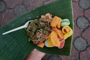 molho de amendoim misturado com vegetais é um alimento típico indonésio chamado gado gado envolto em folhas de bananeira foto