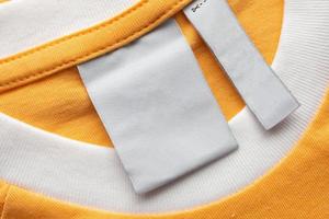 etiqueta de roupas de lavanderia branca em branco no fundo de textura de tecido amarelo foto