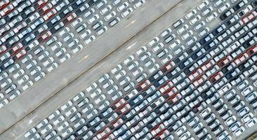 vista aérea do estoque de carros novos no estacionamento da fábrica. acima ver muitos carros estacionados em uma fileira. indústria automobilística. negócios de logística e cadeia de suprimentos. importar ou exportar carros novos no armazém perto do porto. foto