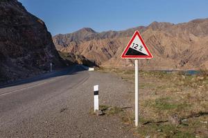 sinal de descida íngreme. sinal de estrada de aviso nas montanhas. doze por cento foto