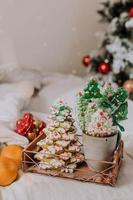 doces de natal, pão de gengibre pintado com glacê, pirulitos e merengues em forma de árvores de natal e tangerinas em uma linda bandeja. bolos caseiros. comida deliciosa para as férias de inverno foto