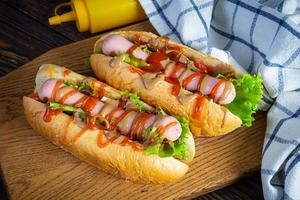 delicioso cachorro-quente com ketchup e mostarda em fundo de madeira. comida de rua foto