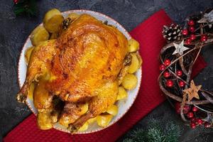 frango assado e batata com decoração de natal. comida tradicional para o natal ou dia de ação de graças foto